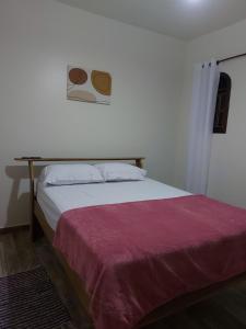 1 dormitorio con 1 cama con manta roja en Recanto Casa Amarela, en Miguel Pereira