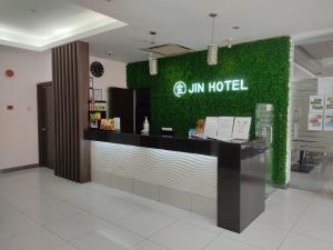 a hotel with a green wall and a counter at Jin Hotel in Puchong