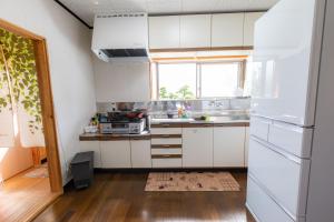 a kitchen with white cabinets and a window at Goto I-House in Goto