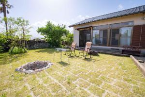 un jardin avec deux chaises et un foyer extérieur dans l'établissement Goto I-House, à Goto