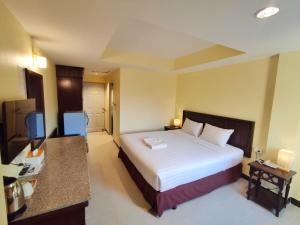 una camera con un grande letto bianco e una scrivania di The Chanthong Residence and Hotel Pattaya a Pattaya Sud