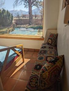 um quarto com um sofá e uma janela com vista em Adorable Adobe Taos - excellent location between ski valley and town! em El Prado