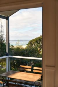 a table on a balcony with a view of the ocean at Surf Beach Narooma Holiday Park in Narooma