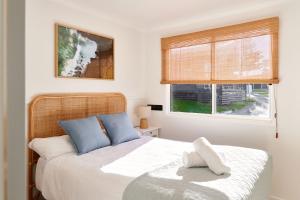a bedroom with a bed with blue pillows and a window at Surf Beach Narooma Holiday Park in Narooma