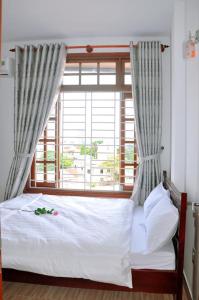 フエにあるHoa ban Homestayの窓のある白いベッドのある寝室
