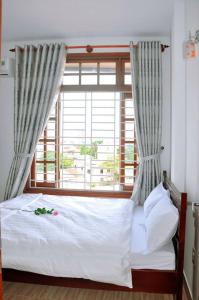 a bed in a room with a large window at Hoa ban Homestay in Hue
