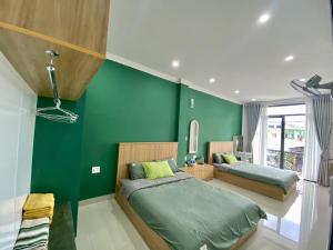 1 Schlafzimmer mit 2 Betten und einer grünen Wand in der Unterkunft SÂM LÂM HOUSE - Bảo Lộc in Bảo Lộc