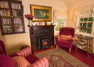 a living room with a fireplace and two chairs at Spetts Cottage in Walhalla