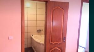 La salle de bains est pourvue d'un lavabo et d'une porte en bois. dans l'établissement Номера та Паркінг- Rooms & Parking, à Tchernivtsi
