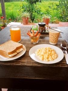a table with two plates of food and toast and orange juice at Brisas del Río in Mindo