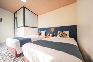 two beds in a room with white and blue at Catba Papillon Garden Bungalows & Resort in Cat Ba