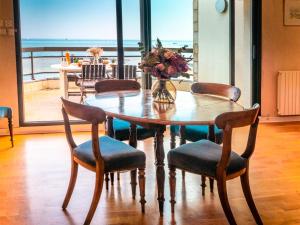 einen Esstisch mit Stühlen und eine Vase mit Blumen in der Unterkunft Larmor-Plage T4 Spacieux avec Terrasse, Ascenseur et Parking face à la Mer - FR-1-349-124 in Larmor-Plage + 27 Fotos