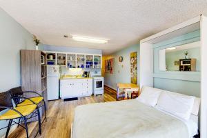 a bedroom with a white bed and a kitchen at Proposal Rock Charmer in Neskowin