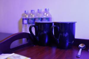 a black mug sitting on a table with bottles of water at J Hotel in Jaffna