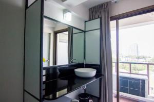 a bathroom with a sink and a large mirror at Regent Ngamwongwan Hotel in Nonthaburi