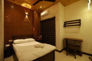 a bedroom with a bed and a brick wall at J Hotel in Jaffna