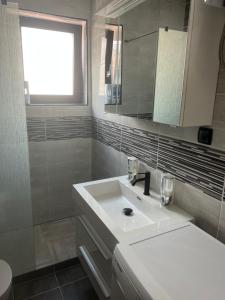 Baño blanco con lavabo y espejo en Sun & More Apartment, en Crikvenica