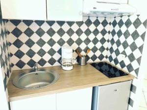 a kitchen counter with a sink and a tiled wall at T1 Centre ville Carré d'or proche plage in Ajaccio +10 photos