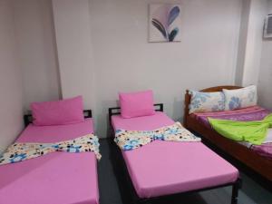 two beds in a room with pink and green sheets at Casa Sarmiento in Laoag