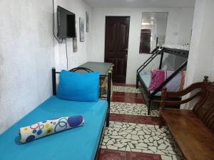 um quarto com uma cama azul e uma televisão em Casa Sarmiento em Laoag