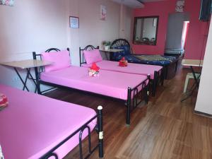 fila de camas en una habitación con sábanas rosas en Casa Sarmiento, en Laoag