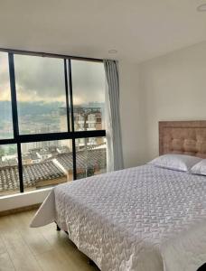 - une chambre avec un lit et une grande fenêtre dans l'établissement Cama Queen, Vista a las Montañas, à Manizales