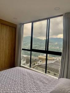 a bedroom with a large window with a view at Cama Queen, Vista a las Montañas in Manizales