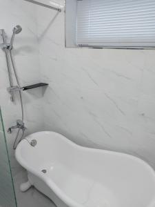 uma banheira branca na casa de banho com uma janela em Pool Story 6 em Jeju