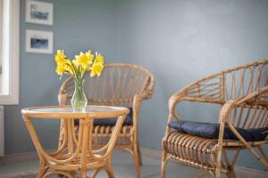 un jarrón de flores amarillas en una mesa junto a dos sillas en Seaside Cottage in Suomenlinna en Helsinki