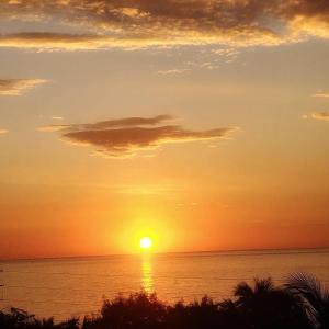una puesta de sol sobre el océano con el sol en el cielo en Marcilia Beach Bungalows en Los Órganos
