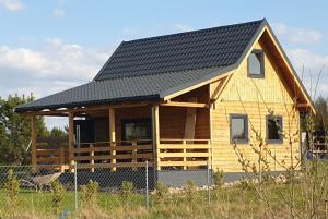 a log cabin with a black roof at Przytulny domek w Brajnikach 86 37 in Jedwabno