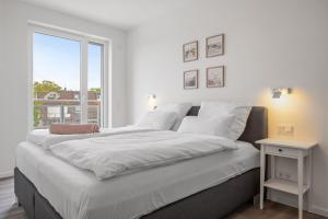 a white bedroom with a large bed and a window at Weiße Villen Weiße Villen 1-11 in Boltenhagen