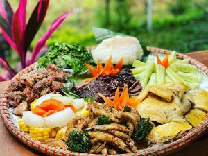 a plate of food with meat and vegetables on a table at 6Senses Garden Homestay in Hòa Bình