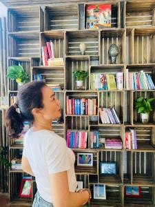 a woman standing in front of a shelf of books at 6Senses Garden Homestay in Hòa Bình