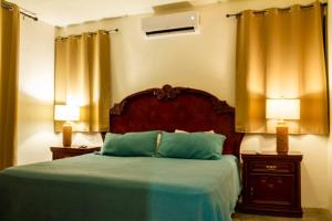 a bedroom with a bed with green sheets and two lamps at Casa Flamingos Altabi in Mérida