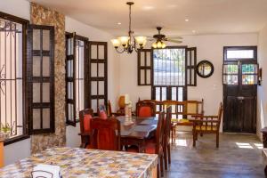 a dining room with a table and chairs and windows at Casa Flamingos Altabi in Mérida