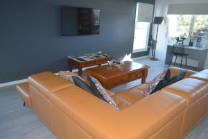 an orange couch in a living room with a table at Monaro House - Hervey Bay in River Heads
