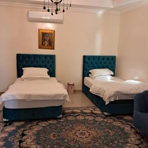 two beds in a bedroom with blue headboards at Sara Farm in Abu Dhabi