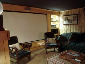 a large screen in a living room with chairs and a couch at Chalet bois 9 pers, Grand confort, près pistes et commerces, Wi-Fi, Equipé, Parking, Non fumeur - FR-1-733-18 in Crest-Voland