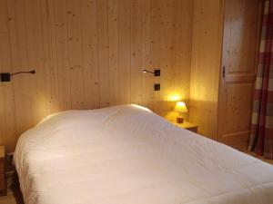 a white bed in a room with wooden walls at Appartement 6 pers, 3 ch, centre village, avec WIFI et poêle à granules - FR-1-733-85 in Crest-Voland