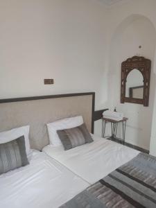 1 dormitorio con 1 cama blanca grande y espejo en Atlas Resorts, en Aït Ourir
