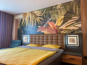 ein Schlafzimmer mit einem Bett und einem tropischen Gemälde an der Wand in der Unterkunft Hotel Atol in Sonnenstrand