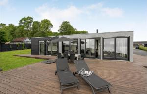 a house with a deck with chairs and an umbrella at 3 Bedroom Lovely Home In Haderslev in Kelstrup