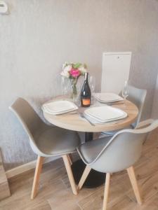 una mesa de madera con 2 sillas y una botella de vino en Leśne Apartamenty en Szczytno