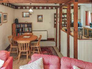 a living room with a table and a kitchen at Hunt Cottage in Sharrington