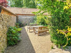 a garden with two wooden benches and a table at Hunt Cottage in Sharrington