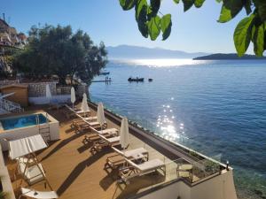 a deck with chairs and a swimming pool next to the water at TRL Lefkada in Nydri