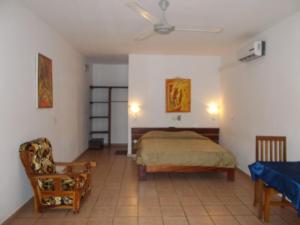 um quarto com uma cama e uma cadeira em Hôtel Alizé Plage em Baguida