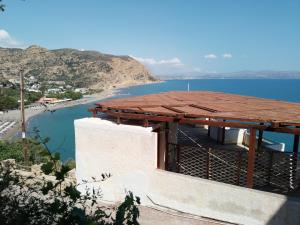 a building with a roof next to a body of water at Loggia Two in Agia Galini