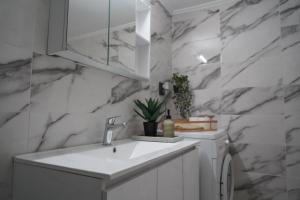 a bathroom with a white sink and marble walls at Jelinas bright apartment in the centre of Nafplio in Nafplio